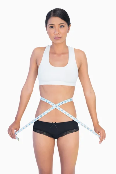 Serious slim woman measuring her waist — Stok fotoğraf