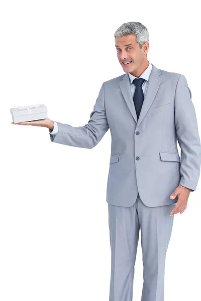 Handsome businessman holding gift and looking at camera — Stock Photo, Image