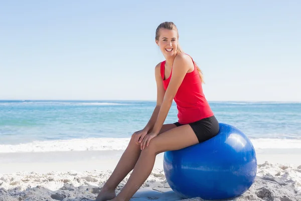 Athletische junge Frau sitzt auf Gymnastikball und blickt in die Kamera — Stockfoto