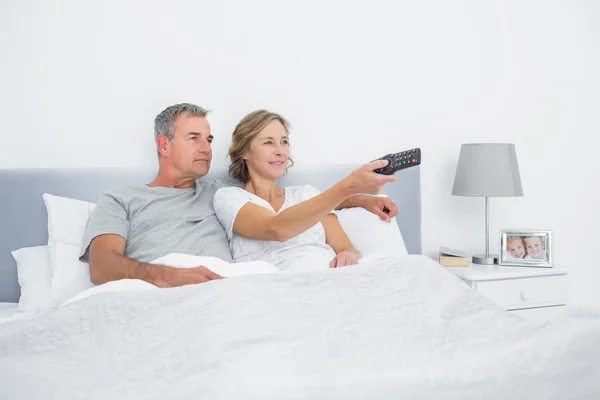 Ευτυχισμένο ζευγάρι βλέποντας τηλεόραση στο κρεβάτι — Φωτογραφία Αρχείου