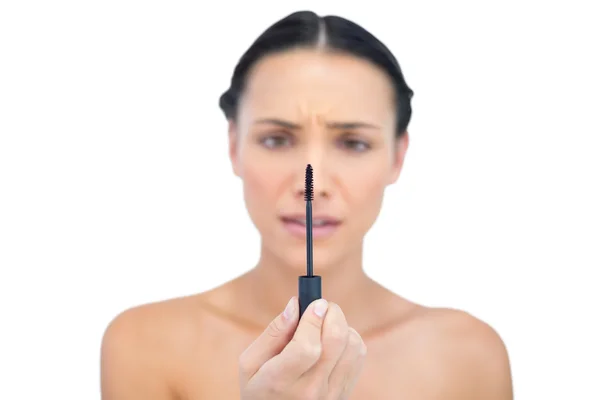 Annoyed young brunette looking at her mascara — Stock Photo, Image