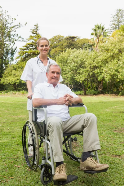 Gelukkig man in een rolstoel zit met zijn verpleegster die hem duwen — Stockfoto