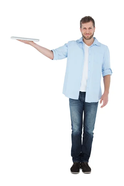 Smiling model holding laptop on right hand looking at camera — Stock Photo, Image