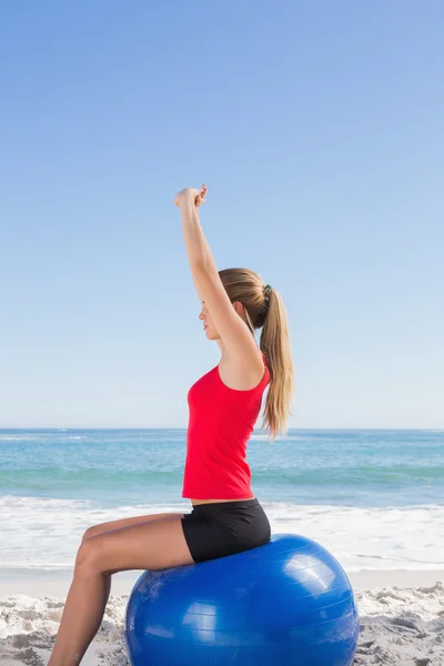 Fitte Frau sitzt auf Gymnastikball und streckt Arme — Stockfoto