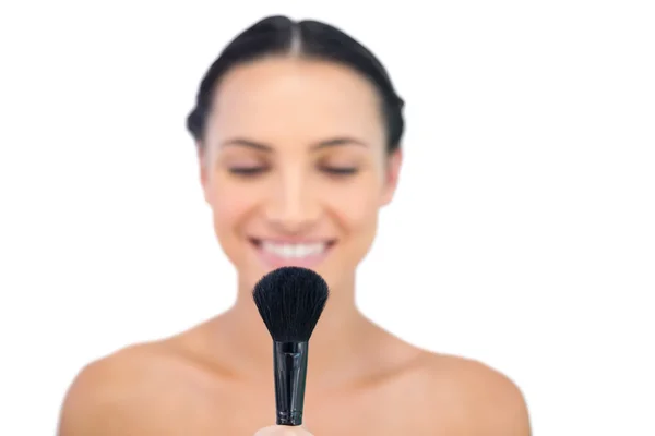 Smiling natural brunette holding powder brush — Stock Photo, Image