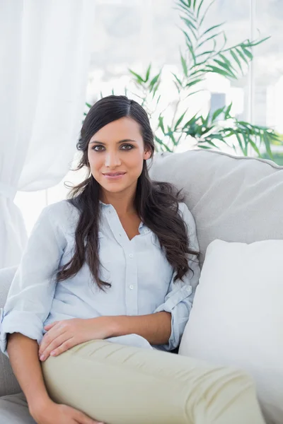 Gorgeous brunette sitting on the couch — Stock Photo, Image