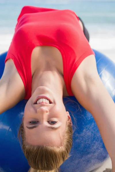 Die fitte Blondine streckt sich auf dem Trainingsball zurück und blickt in die Kamera — Stockfoto