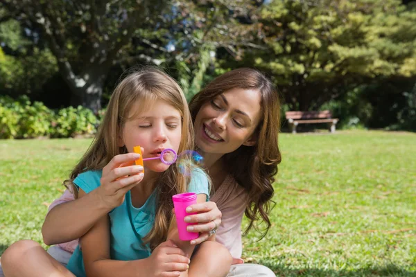 Daughter blowing bubbles with mother — Stock Photo, Image