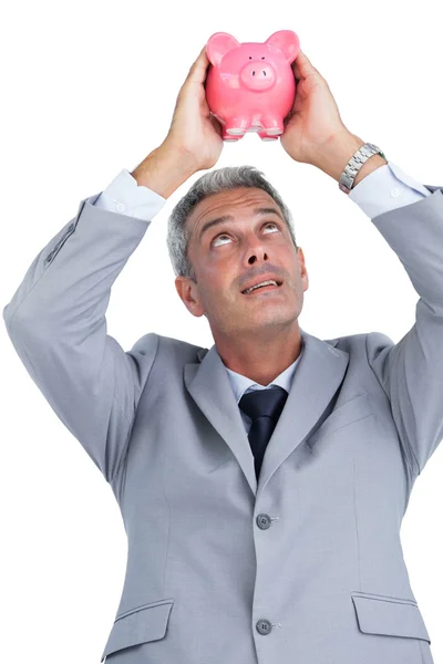 Curious businessman holding piggy bank above his head — Stock Photo, Image