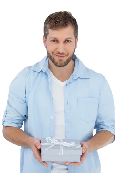 Happy man holding a gift looking at camera — Stock Photo, Image