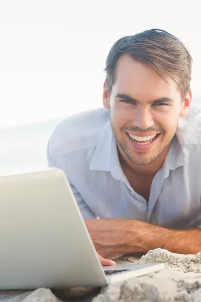 Gelukkig knappe man op het strand met zijn laptop — Stockfoto