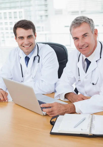 Médicos posando enquanto trabalham juntos no laptop — Fotografia de Stock