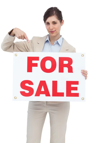 Estate agent holding and pointing to for sale sign — Stock Photo, Image