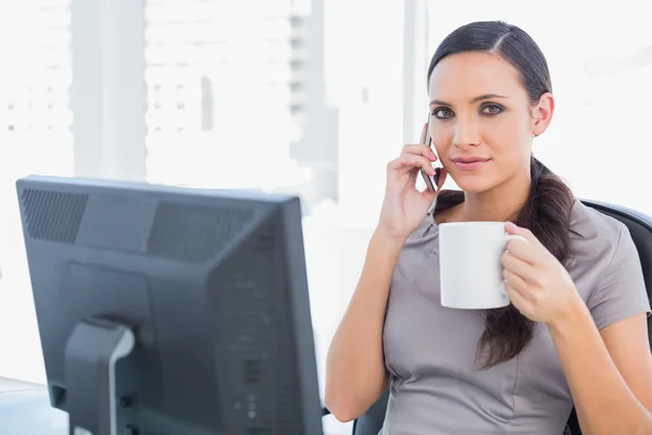 Relaxado empresária segurando seu café e telefone — Fotografia de Stock