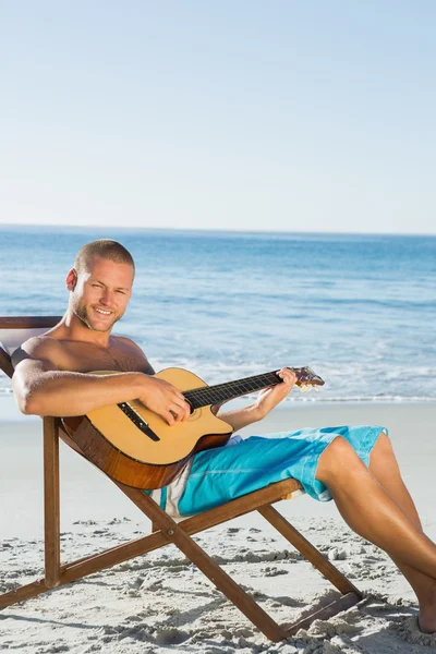 Iloinen komea mies strumming kitara — kuvapankkivalokuva