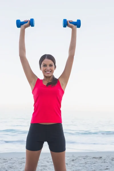 Mujer deportiva sonriente sosteniendo pesas — Foto de Stock