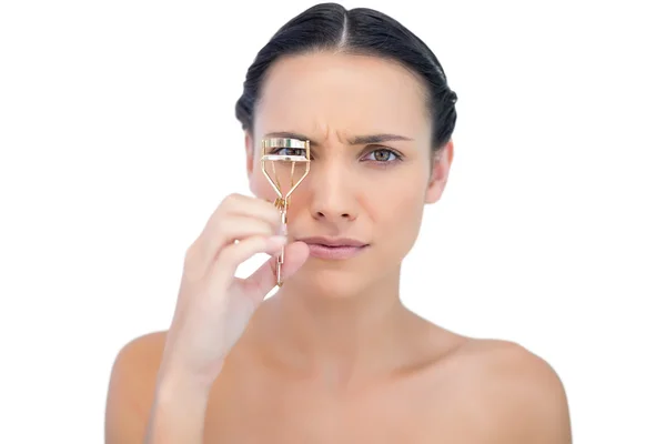 Serious natural brunette with eyelash curler — Stock Photo, Image