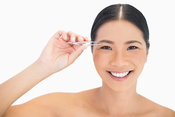 Cheerful natural model using tweezers for her eyebrow — Stock Photo, Image