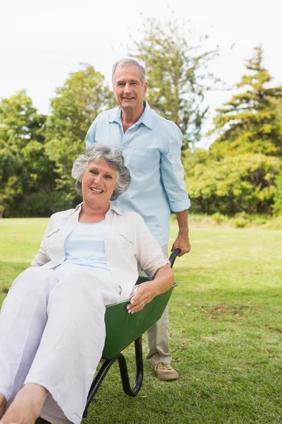 Domme man zijn vrouw duwen in een kruiwagen — Stockfoto