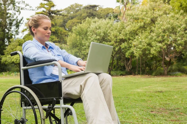 Jeune femme en fauteuil roulant avec un ordinateur portable — Photo