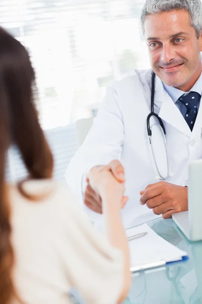 Médico sonriente dándole la mano a su paciente — Foto de Stock