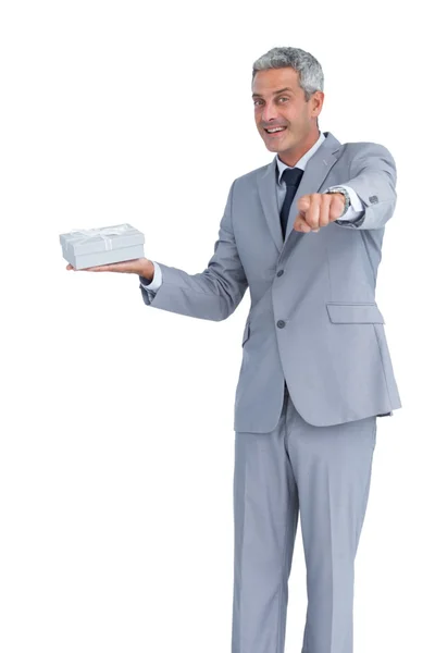 Good looking businessman offering gift and pointing at camera — Stock Photo, Image