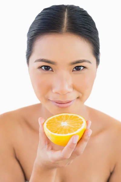 Spokojnej ładna kobieta trzymając plasterek pomarańczy w ręku — Zdjęcie stockowe