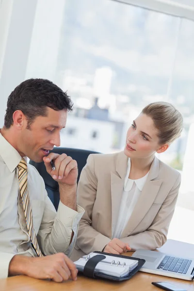 Empresário consultando sua agenda enquanto conversava com seu colega — Fotografia de Stock