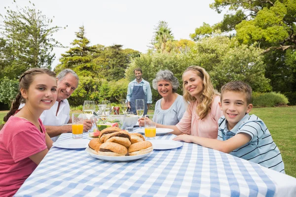 Uitgebreide familie wachten voor barbecue wordt gekookt door vader glimlachen — Stockfoto