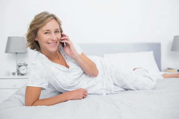 Innehåll blond kvinna liggande på sängen att göra ett telefonsamtal — Stockfoto