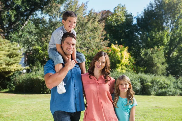 Cute family smiling at camera in the park — Stock Photo, Image