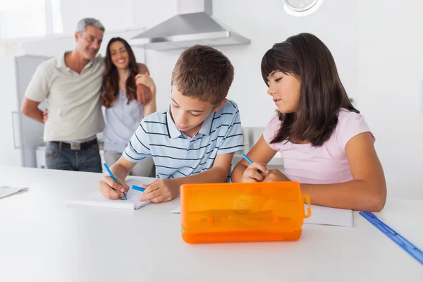 Broers en zussen tekenen samen in keuken met hun ouders glimlachen — Stockfoto