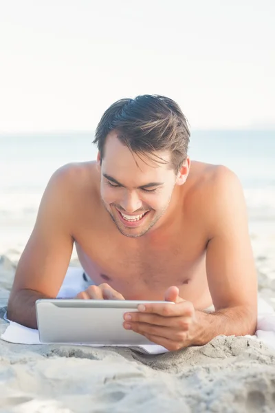 Onun tableti kullanarak havlusunu yatan yakışıklı adam — Stok fotoğraf