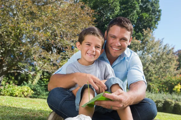 Smiling dad and son holding a leaf — Stock Photo, Image