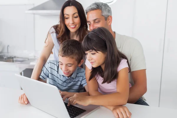 Família sentada na cozinha usando seu laptop — Fotografia de Stock