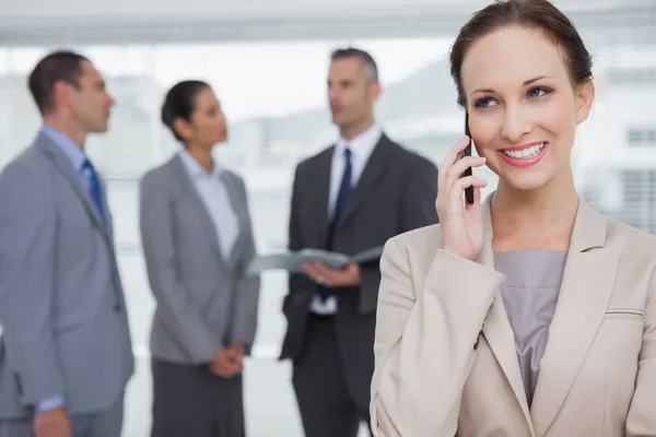 Smiling businesswoman calling while colleagues talking together — Stock Photo, Image