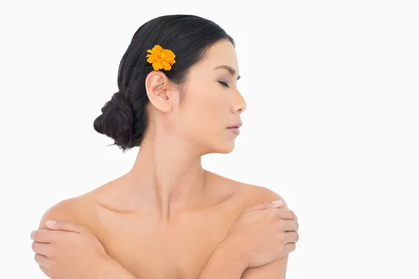 Nachdenkliches Model mit orangefarbener Blume im Haar, die ihre Schultern berührt — Stockfoto