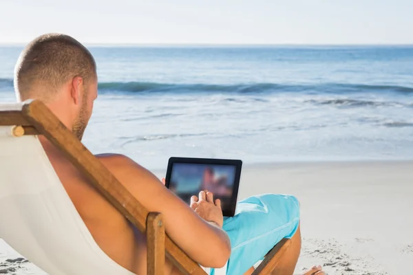 Hombre guapo desplazándose en su PC tableta mientras toma el sol — Foto de Stock