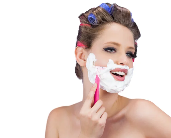 Happy model in hair curlers posing with razor — Stock Photo, Image