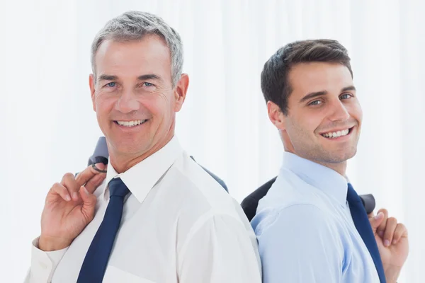 Sonrientes hombres de negocios posando juntos mientras sostienen t —  Fotos de Stock