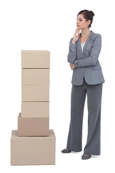 Thoughtful businesswoman with cardboard boxes — Stock Photo, Image