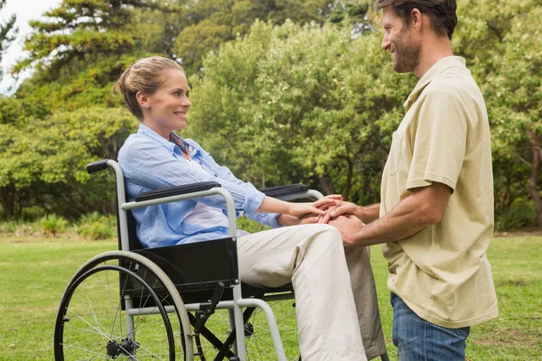 Attraktiv kvinna i rullstol med partner på knä bredvid henne — Stockfoto