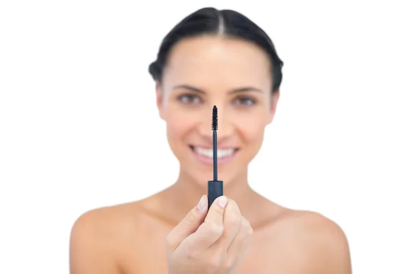 Cheerful young brunette looking at her mascara — Stock Photo, Image