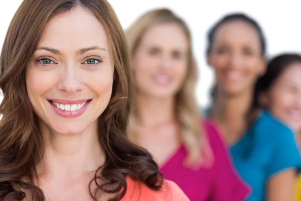 Smiling models in a line posing with focus on brunette — Stock Photo, Image