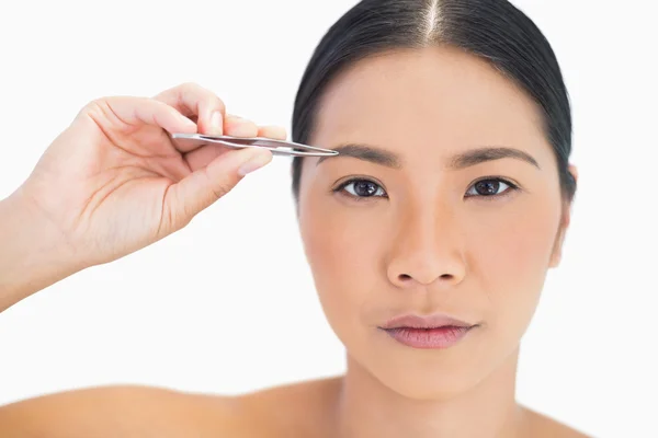 Concentrated natural model using tweezers for her eyebrow — Stock Photo, Image