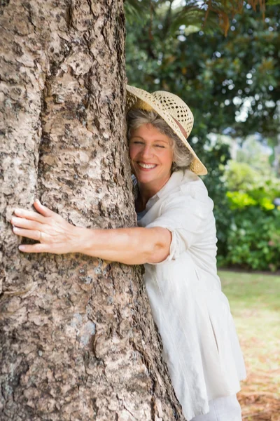 Retired woman hugging a tree and smiling — Stock Photo, Image