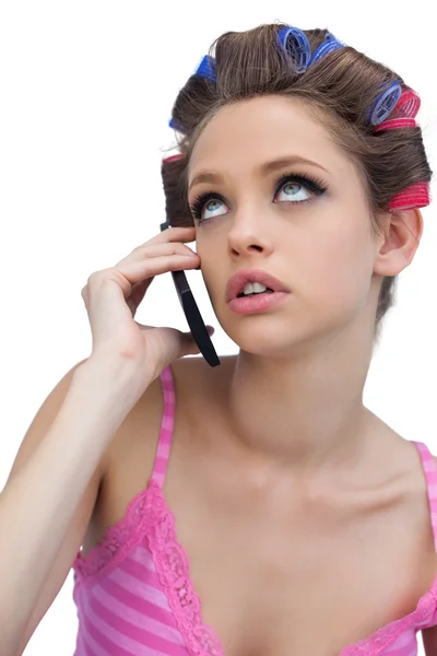 Thoughtful young model wearing hair rollers with phone Stock Image