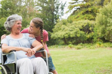 Granddaughter hugging grandmother in wheelchair clipart