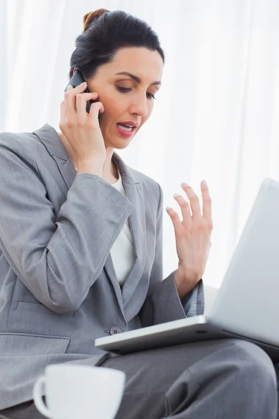 Concentrated businesswoman calling with her mobile phone and usi — Stock Photo, Image