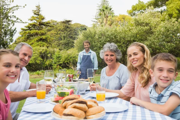 Happy extended family waiting for barbecue being cooked by father — Stock Photo, Image